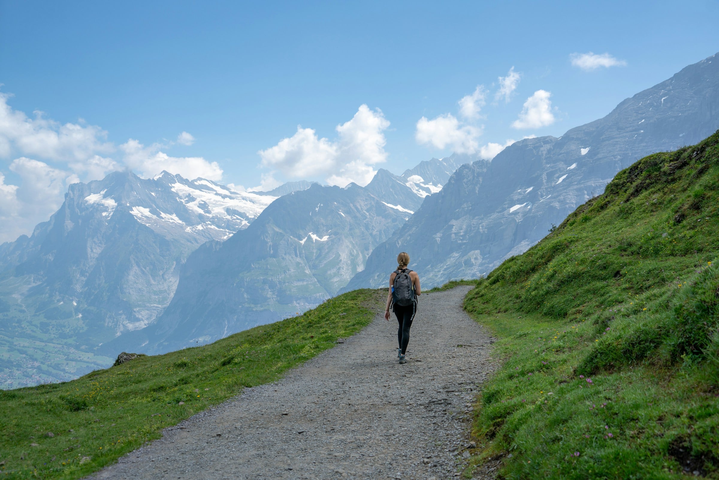 Hiker on an alpine trail with snow-capped Swiss mountains